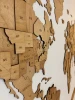 Drewniana mapa świata 3D w kolorze winchester na ścianie w salonie obok regału z książkami